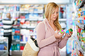 Woman in grocery store comparing two similar jars 