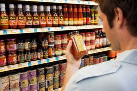 Young man in supermarket reading jar label